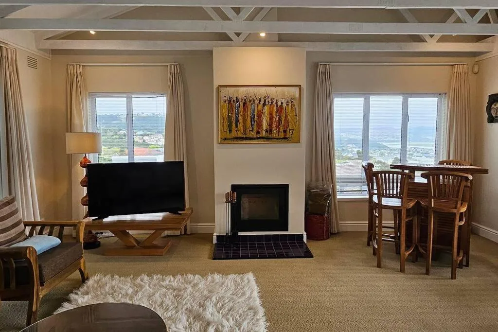 Open-plan lounge with fireplace, TV, and expansive valley views through large windows