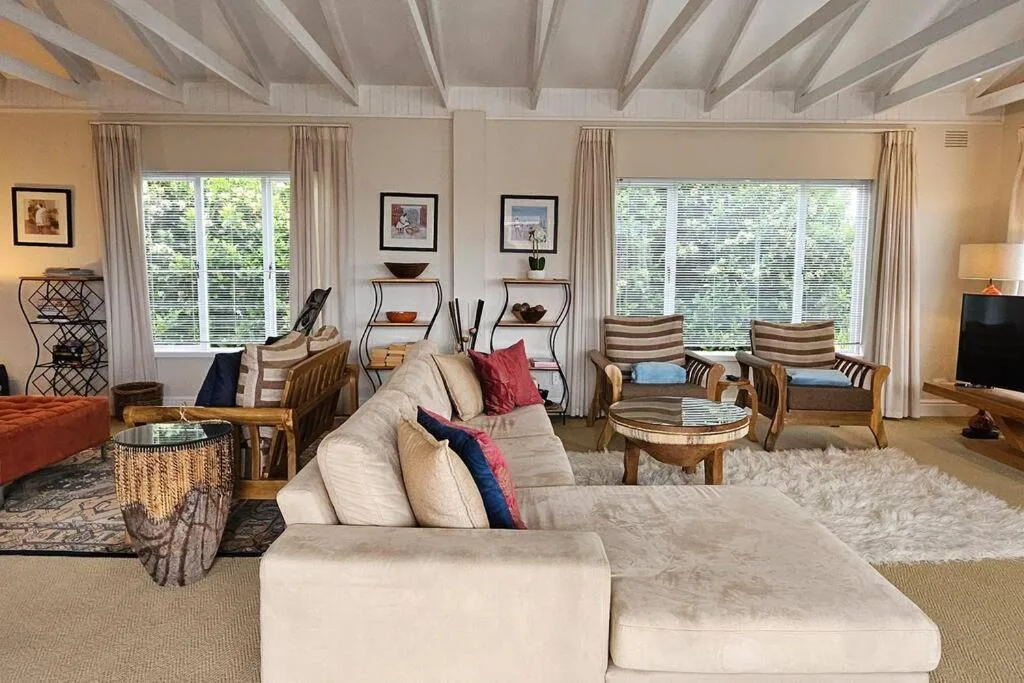 Spacious living room with cream sectional sofa, wooden chairs, and large windows