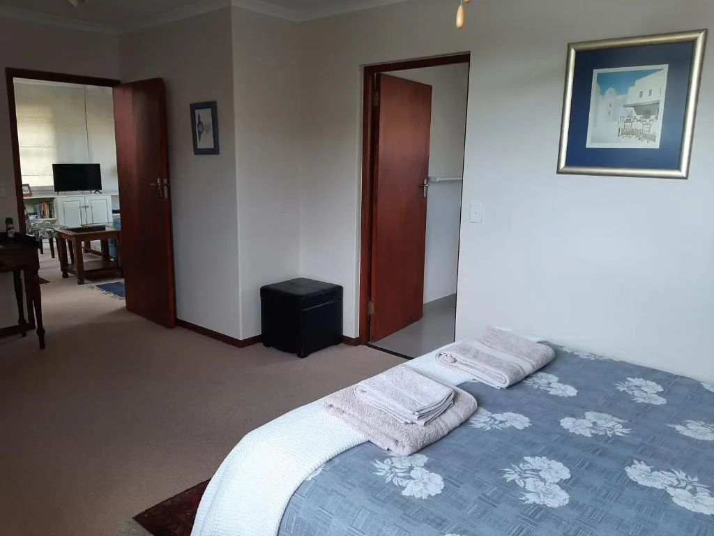 Spacious bedroom with double bed, towels, and open-plan lounge area beyond