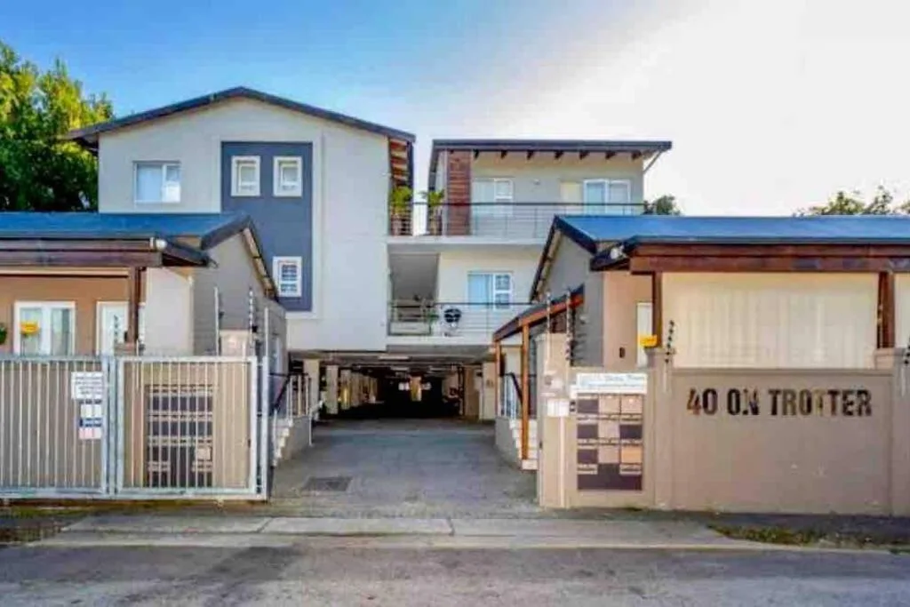 Modern apartment building entrance with gated driveway and blue roof accents