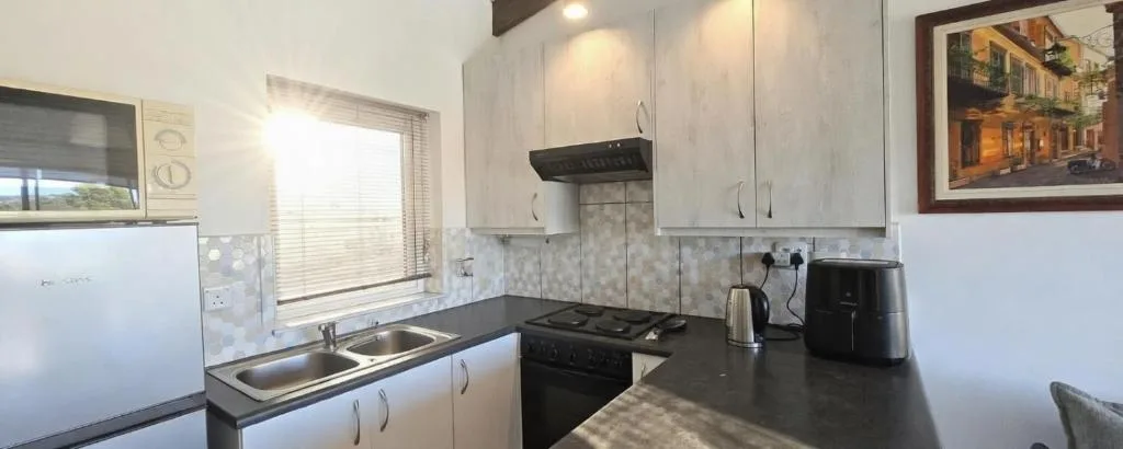 Modern kitchen with gas stove, black countertops, and light cabinetry