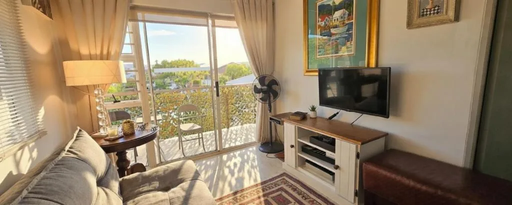 Bright lounge with TV, sofa, and scenic views through glass doors