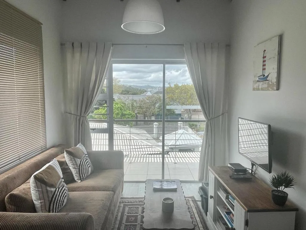 Bright living room with sofa, TV, and large glass doors opening to scenic views