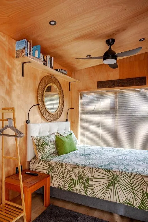 Cozy bedroom with wooden walls, patterned bedding, and ceiling fan