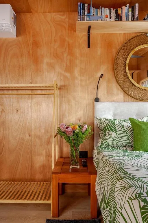Cozy bedroom with tropical bedding, wooden wardrobe, and fresh flowers on nightstand