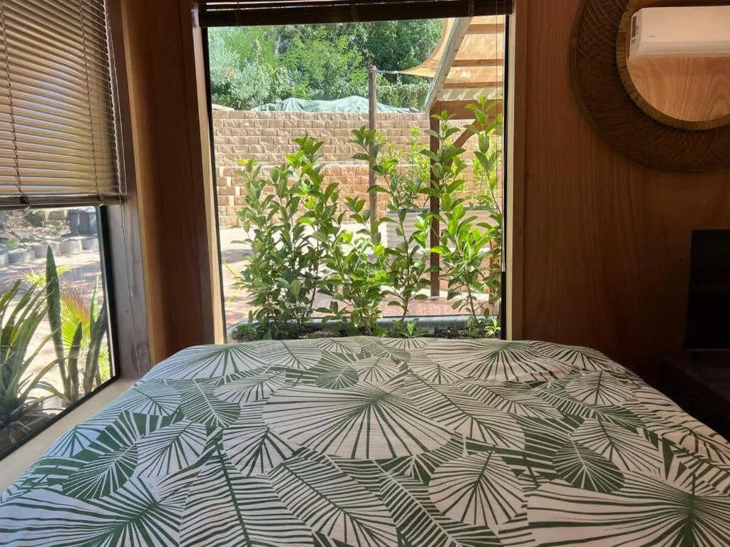 Bedroom with patterned bedding and garden view through large window