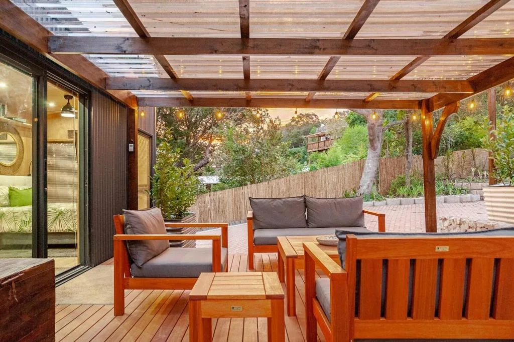 Covered wooden deck with orange furniture and garden views