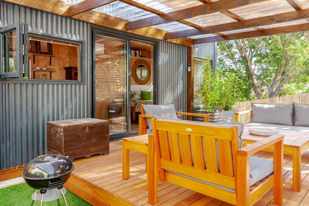 Outdoor deck with wooden furniture, braai grill, and lagoon views