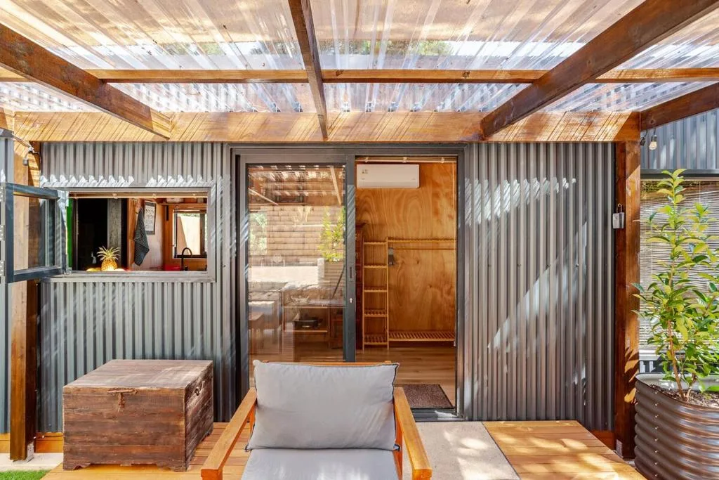 Outdoor seating area with lounge chair and wooden bench under polycarbonate pergola