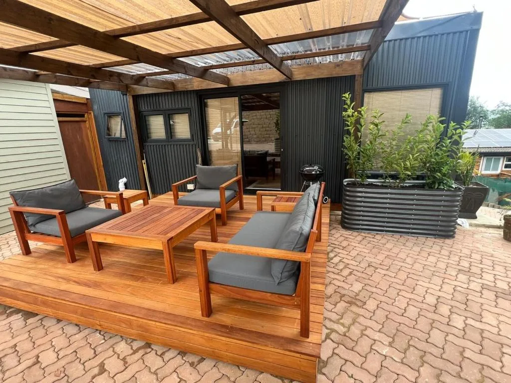 Wooden deck with comfortable seating, pergola, and lagoon views at sunset