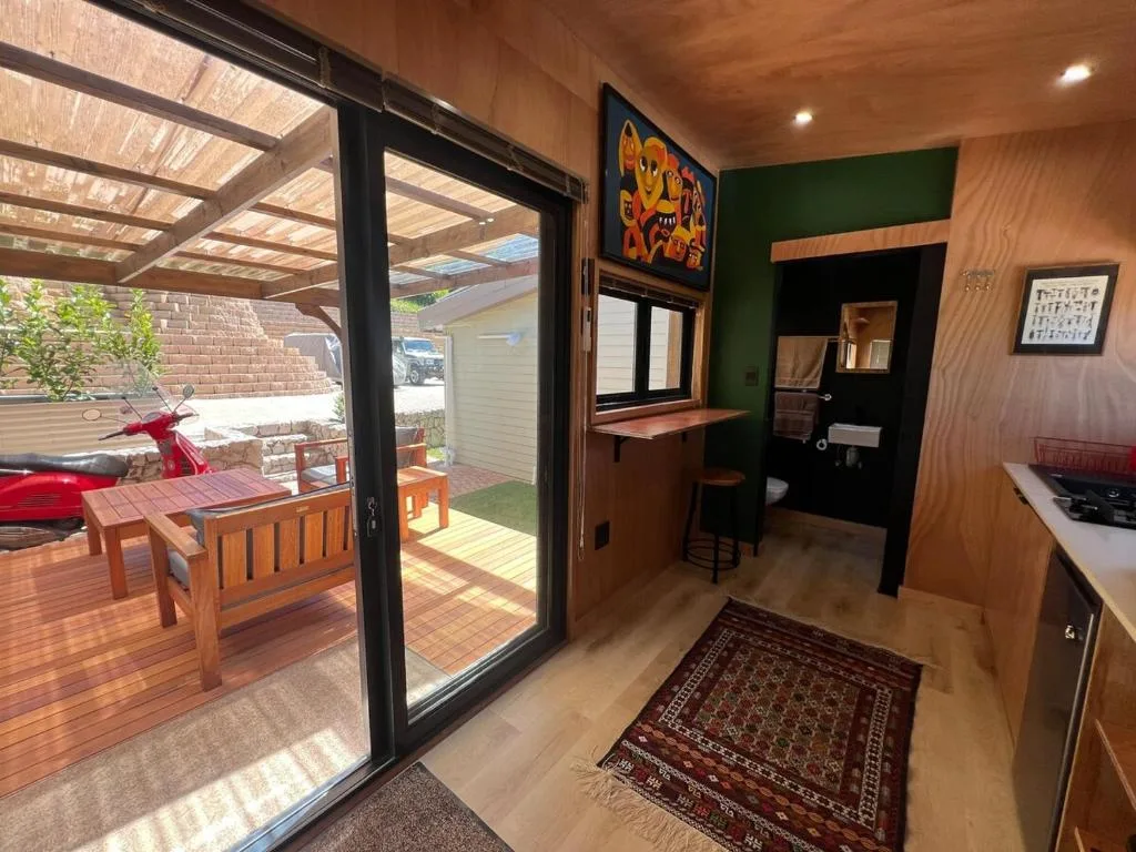 Modern lounge with wooden finishes, colorful artwork, opening to outdoor deck area