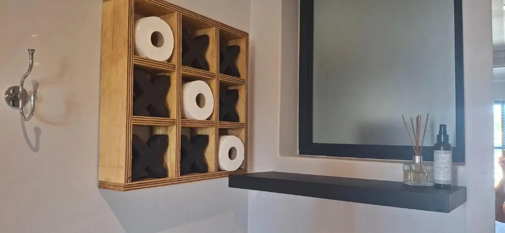 Modern bathroom with wooden toilet paper storage and illuminated mirror