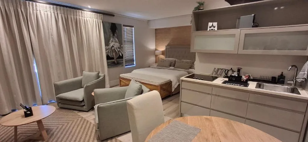 Modern bedroom with kitchenette, lounge seating, and floor-to-ceiling windows
