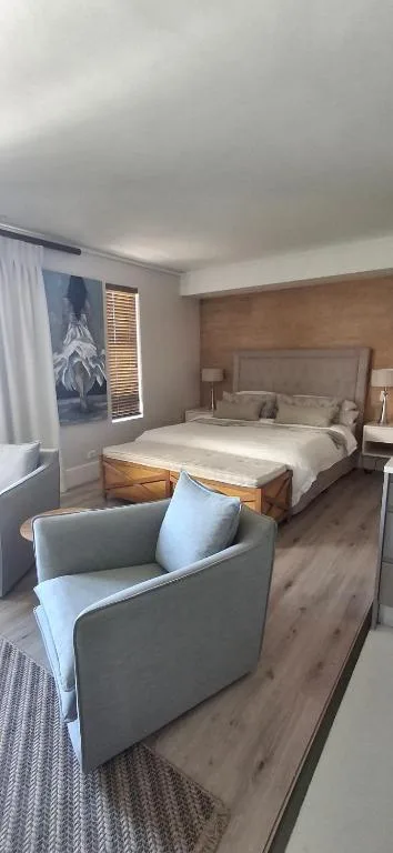Spacious bedroom with upholstered bed, modern furnishings and armchair