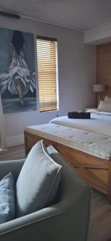 Bright bedroom with wooden bed, decorative wall art, and comfortable seating area