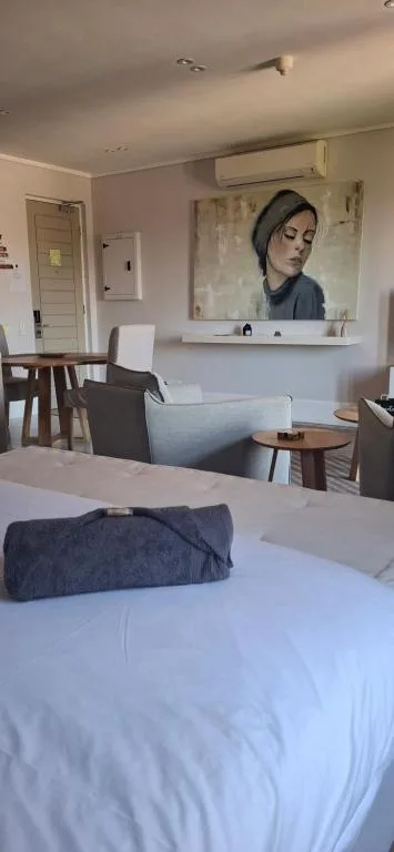 Bedroom with white bed, lounge seating area, and modern wall art