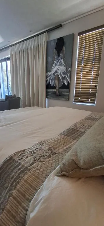 Contemporary bedroom with bed, cream curtains, and artistic wall decor