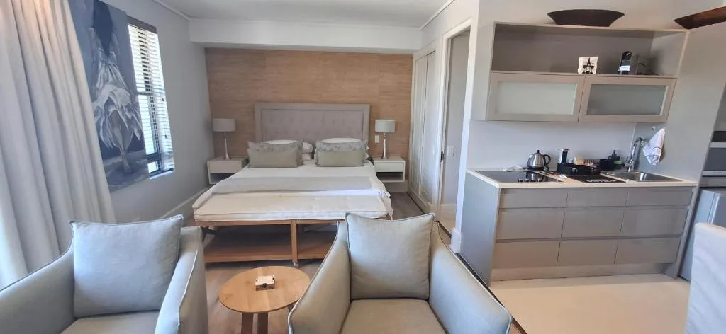 Modern bedroom with queen bed, neutral furnishings, and integrated kitchenette area