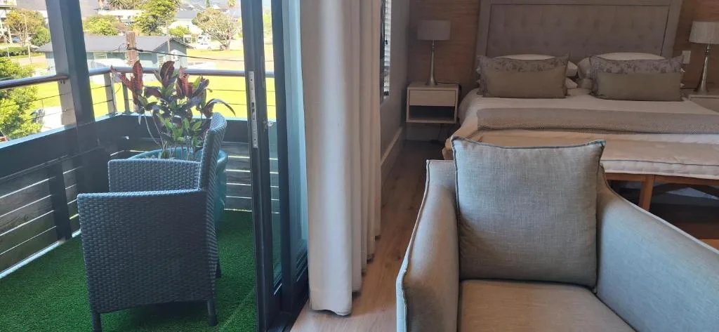 Spacious bedroom with queen bed, armchair, and deck access with garden views
