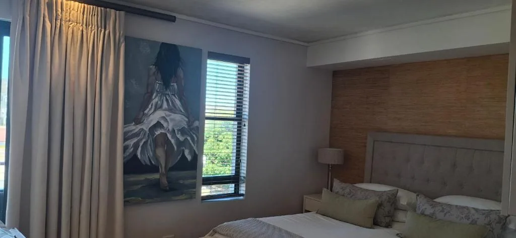 Modern bedroom with wooden headboard, artwork, and garden views
