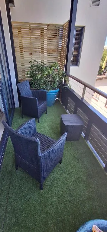 Outdoor balcony with blue armchairs, potted plant, and wooden privacy screen