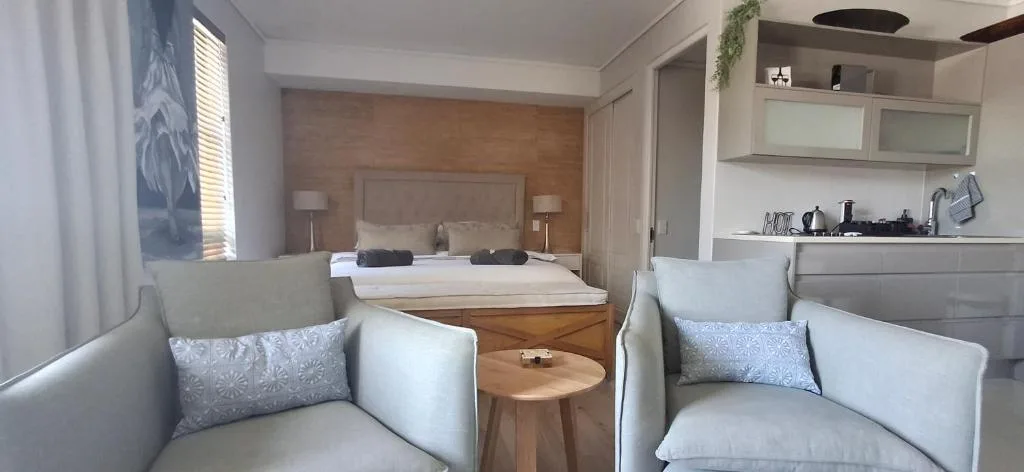 Studio apartment interior showing seating area, bed, and kitchenette in open layout