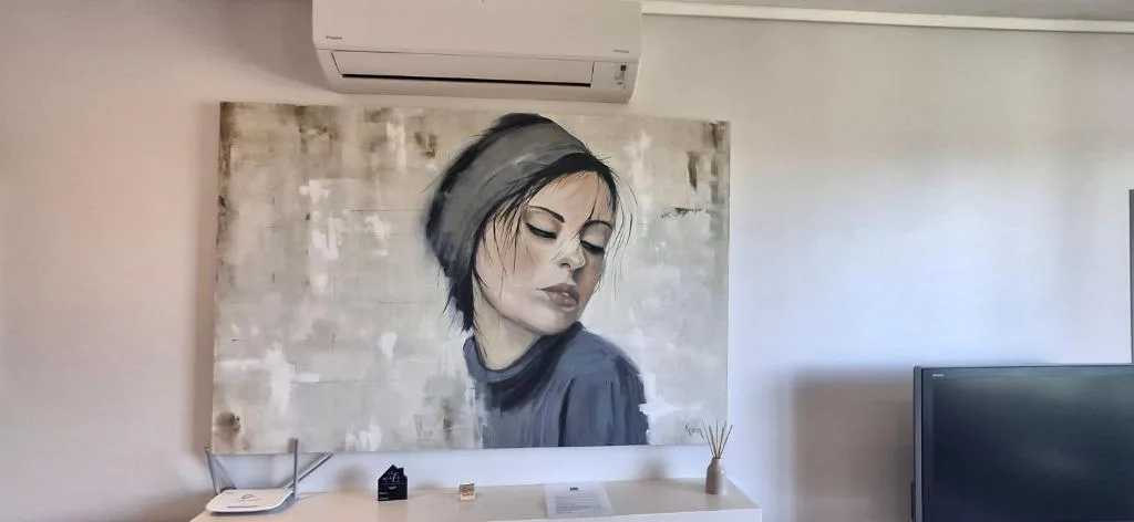 Modern interior with portrait artwork, air conditioning unit, and minimalist desk decor