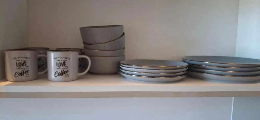 Kitchen shelf with coffee mugs, bowls, and stacked plates displayed