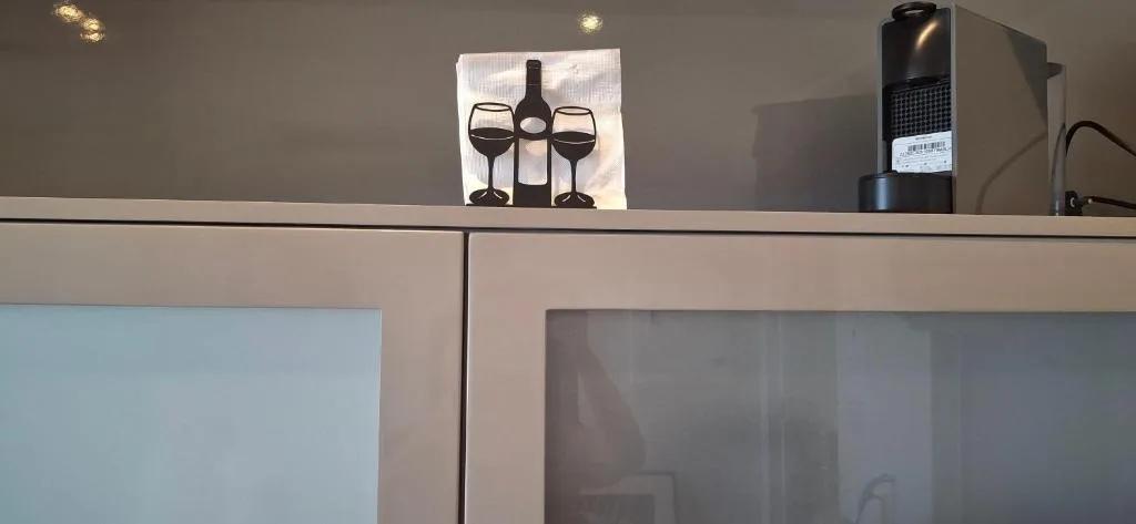 Wine-themed decor and coffee machine on modern shelf above television