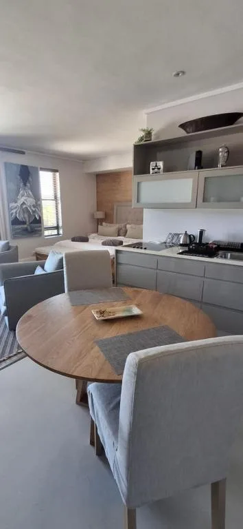 Open-plan dining area with round wooden table and upholstered chairs