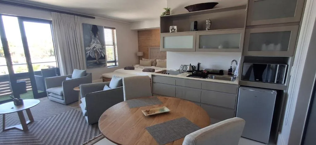 Open-plan dining area with round wooden table and modern kitchen beyond
