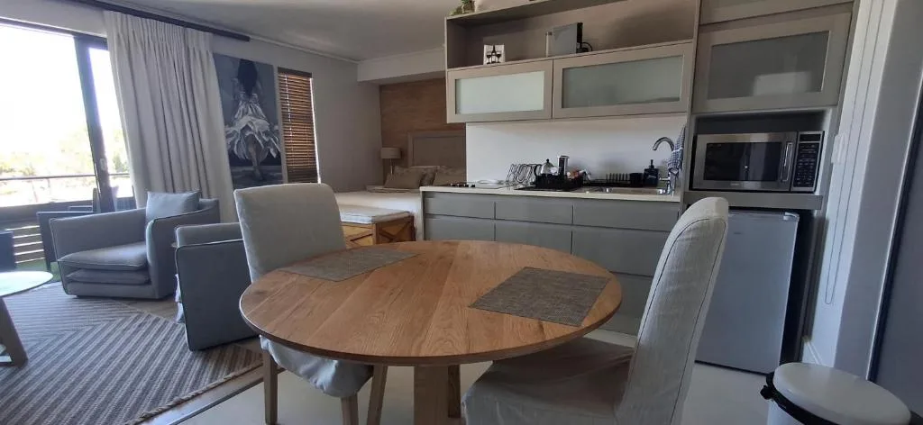 Round wooden dining table with gray upholstered chairs in open-plan apartment