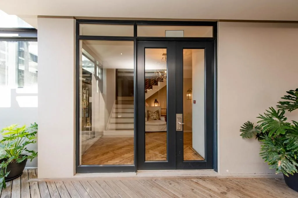 Modern glass sliding doors opening onto wooden deck with potted plants