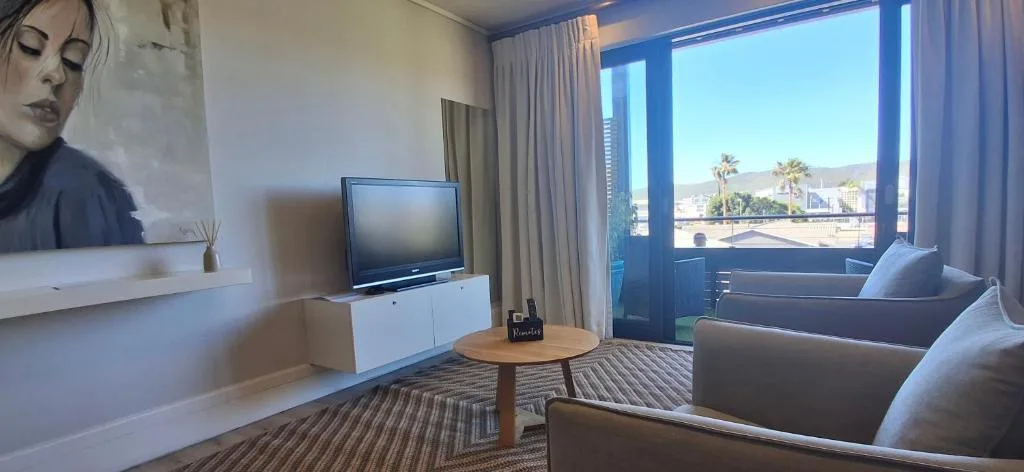 Modern lounge with TV, comfortable seating, and scenic coastal views through large windows