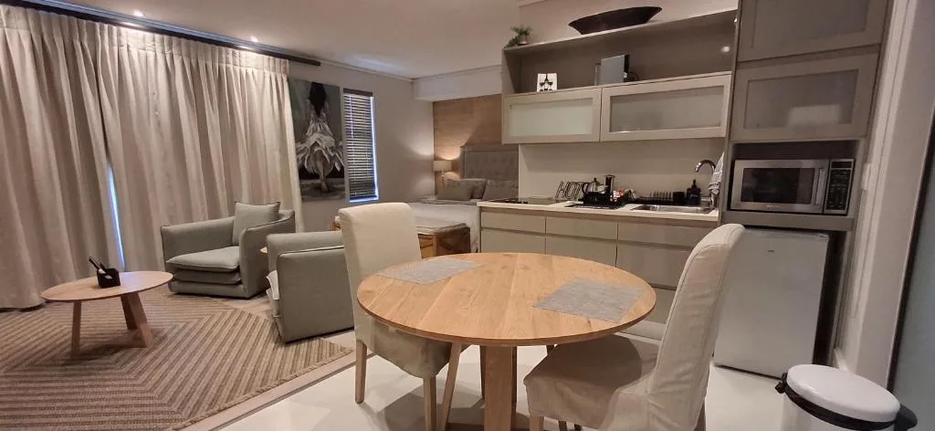 Modern open-plan lounge with dining table, kitchen, and comfortable seating