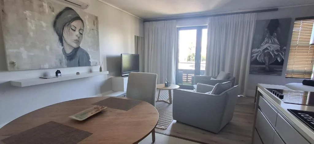 Modern lounge with gray armchairs, round wooden table, and gallery wall art
