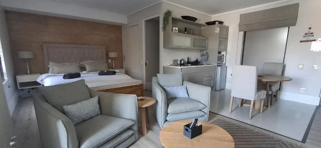 Open-plan lounge with upholstered seating, wooden round table, and modern décor