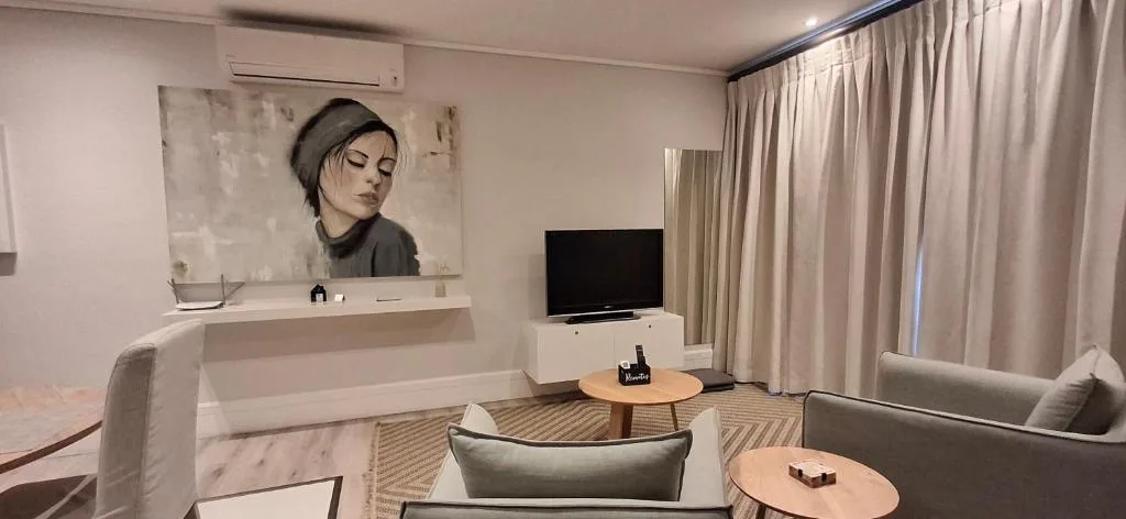 Modern living room with TV, comfortable seating, and contemporary wall art