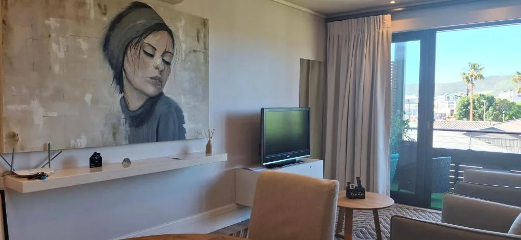 Modern lounge with TV, artwork, and views of Knysna town and mountains