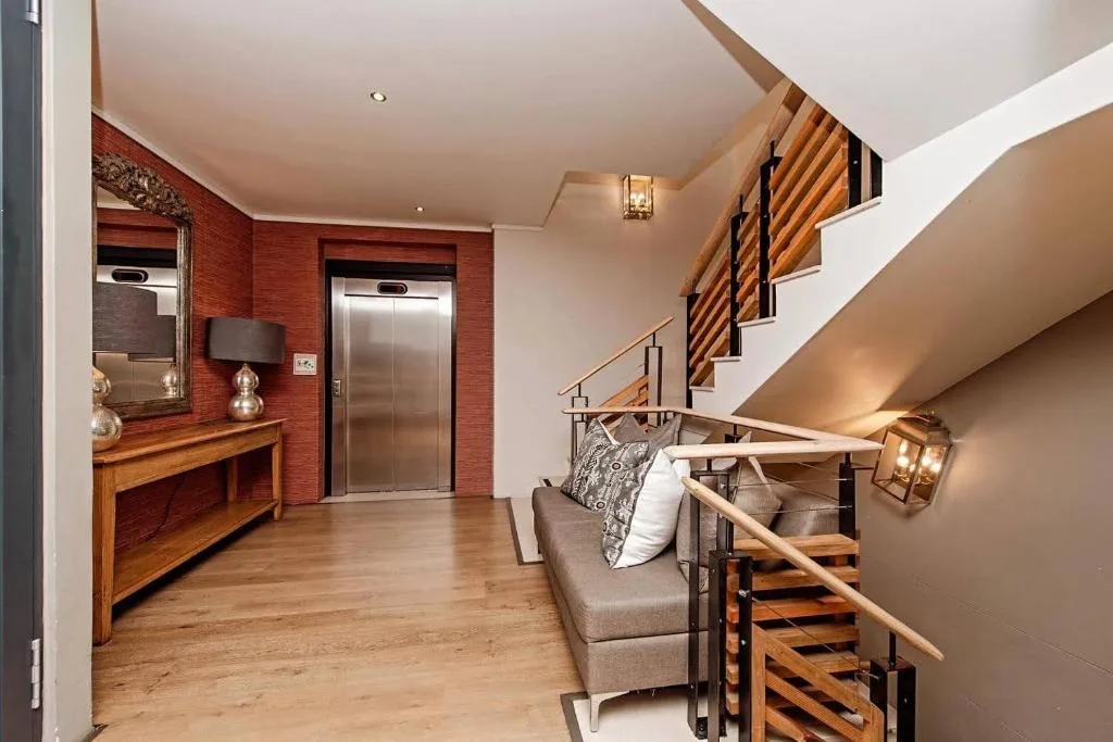 Modern lounge with gray sofa, wooden staircase, and red accent wall
