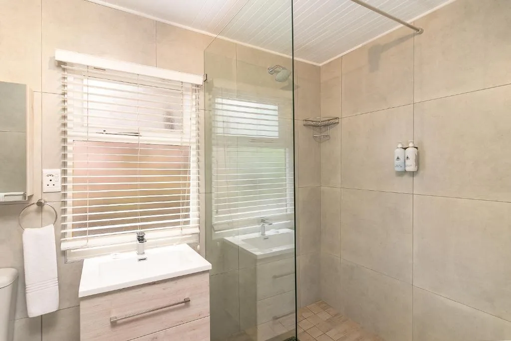 Modern bathroom with double shower, vanity sink, and venetian blind window