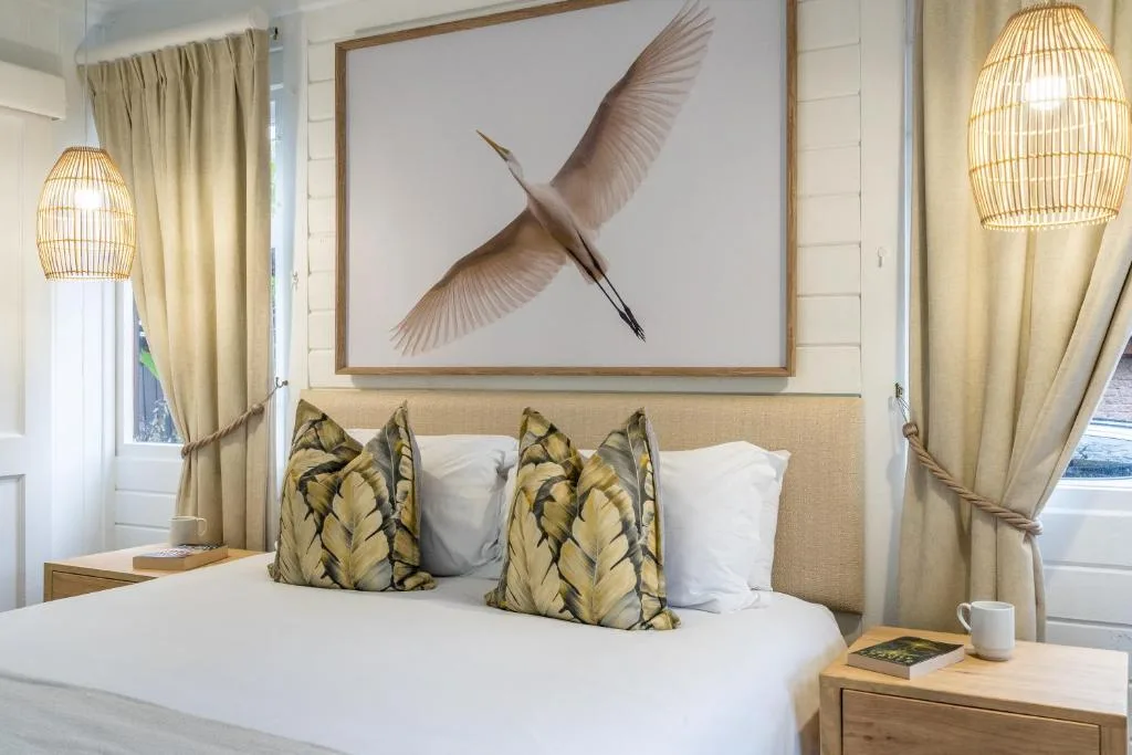 Bedroom with upholstered headboard, patterned pillows, and bird artwork