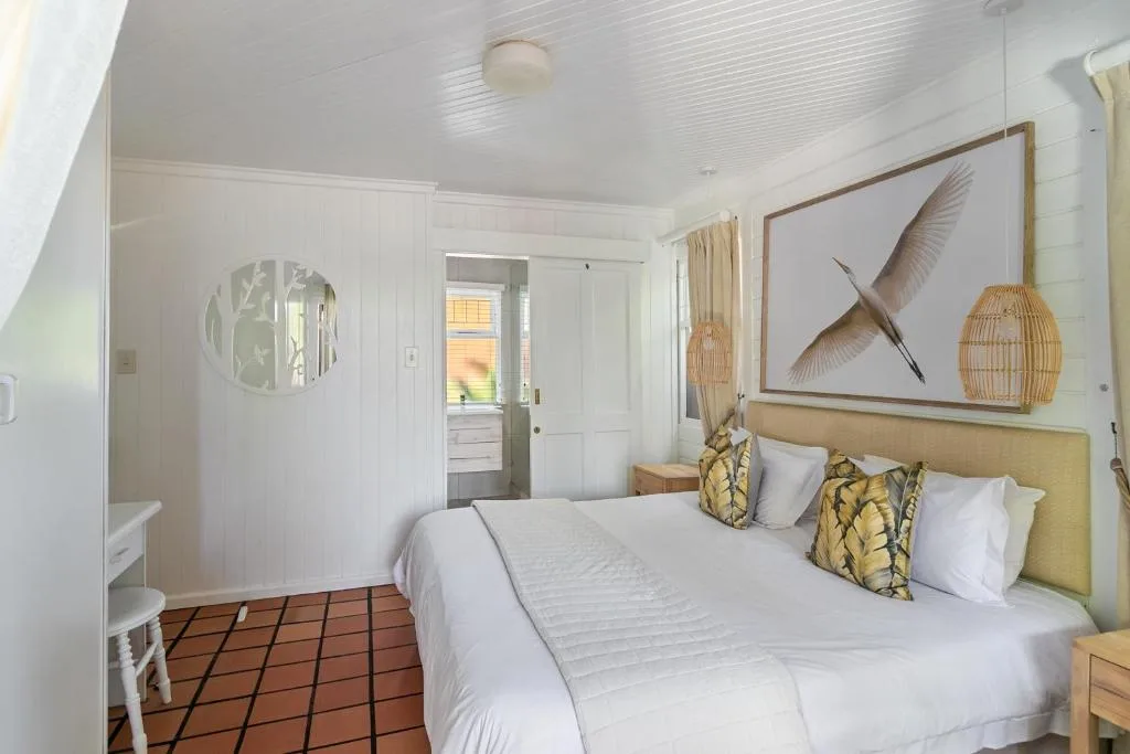 Bright bedroom with queen bed, yellow headboard, and bird artwork