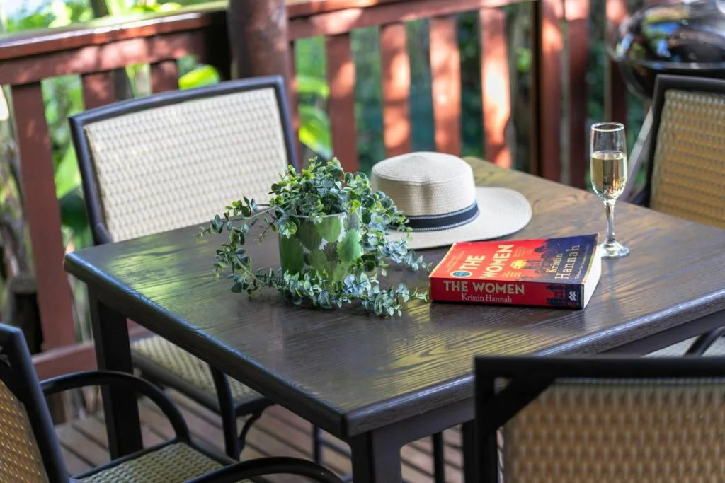 Outdoor deck table with wine glass, potted plant, and book