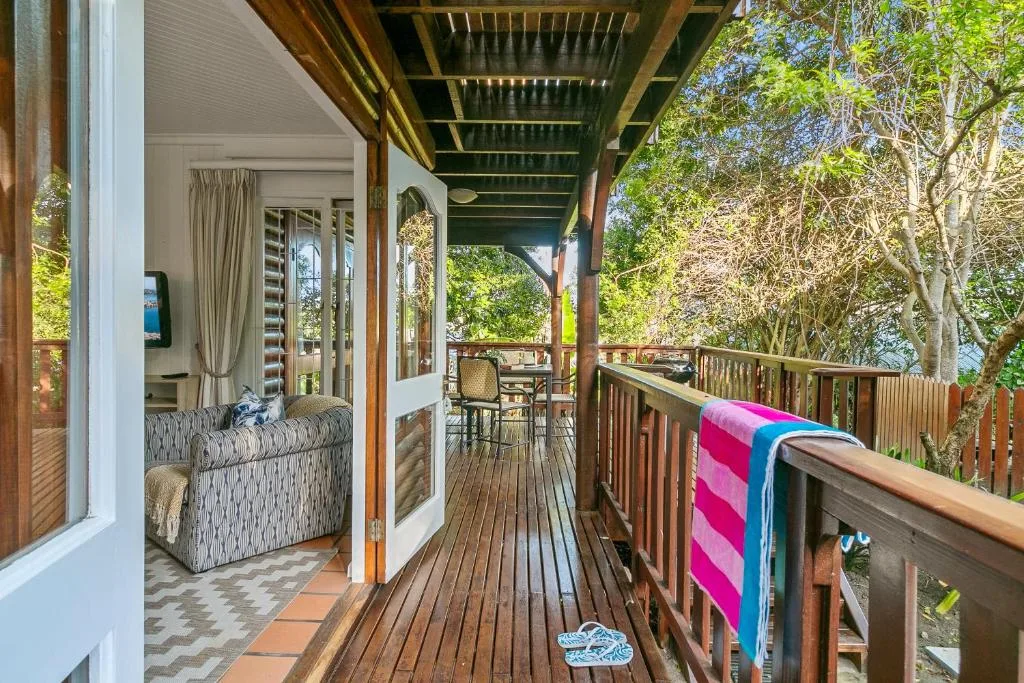 Wooden deck with covered pergola, railing, and forest views surrounding