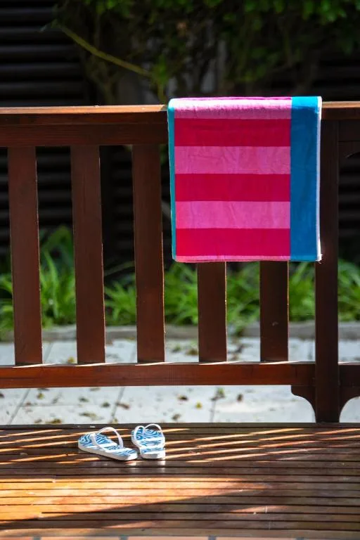 Colorful towel and beach shoes on wooden deck chair