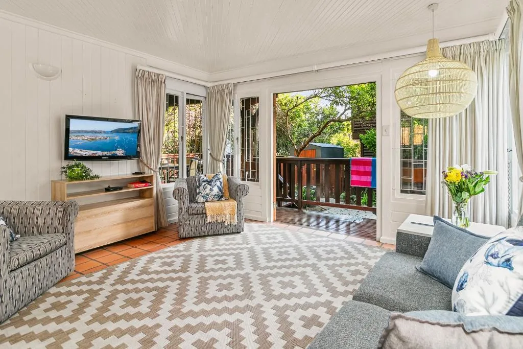 Bright lounge with TV, comfortable seating, and garden views through French doors