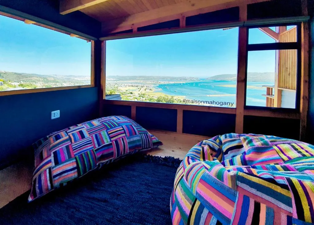 Bedroom with colorful striped bedding and panoramic lagoon views through large windows