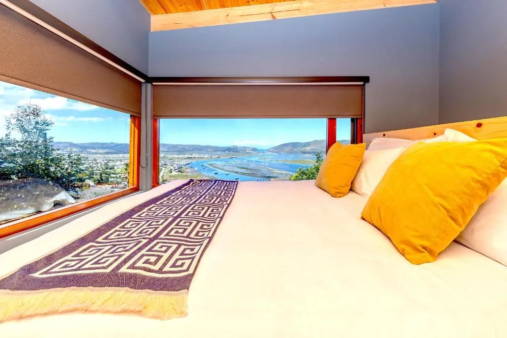 Spacious bedroom with panoramic lagoon views and bright yellow accent pillows