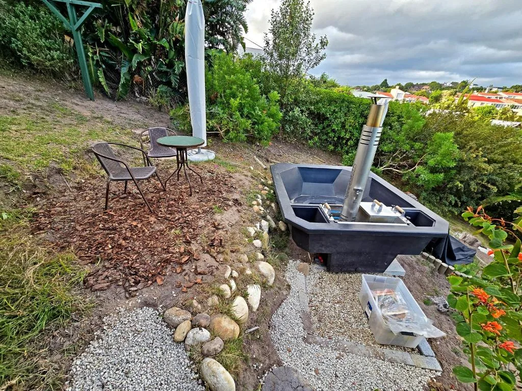 Outdoor braai area with seating, umbrella, and garden views overlooking town